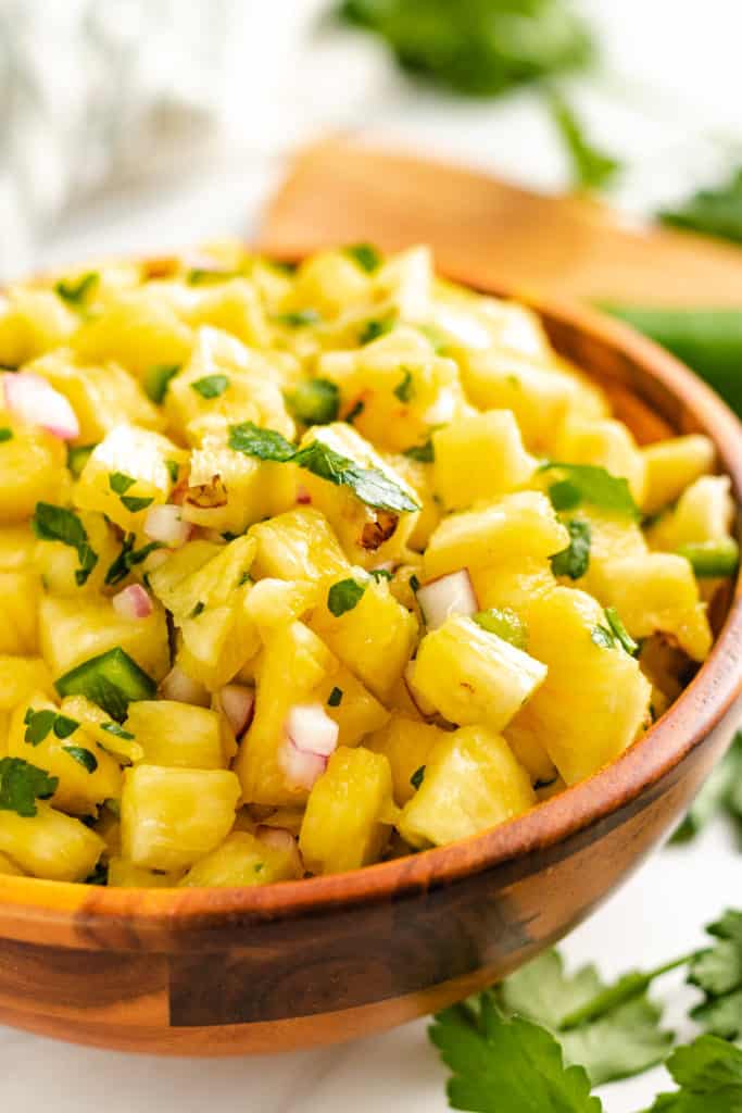 Wooden bowl filled with pineapple jalapeno salsa.