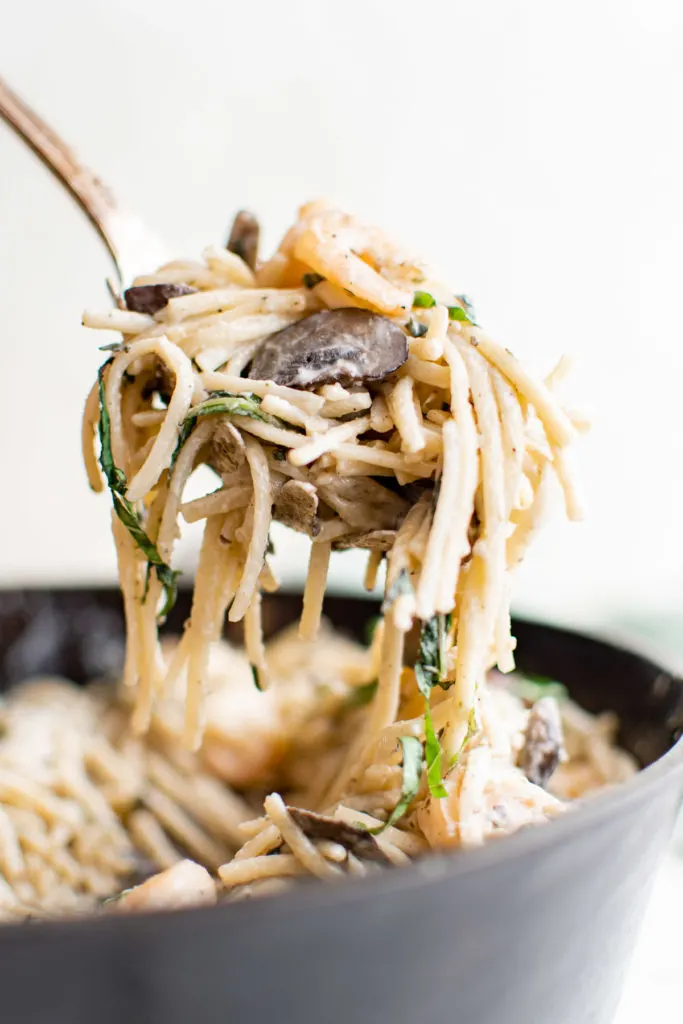 Serving spoon with mushroom shrimp pasta.