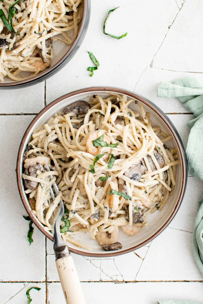 Top down view of pasta with mushrooms and shrimp.