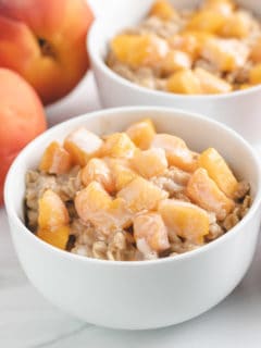 Two bowls of oatmeal topped with fresh peaches.