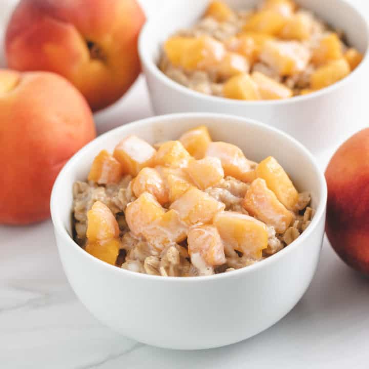 Peaches And Cream Oatmeal Two bowls of oatmeal topped with fresh peaches.