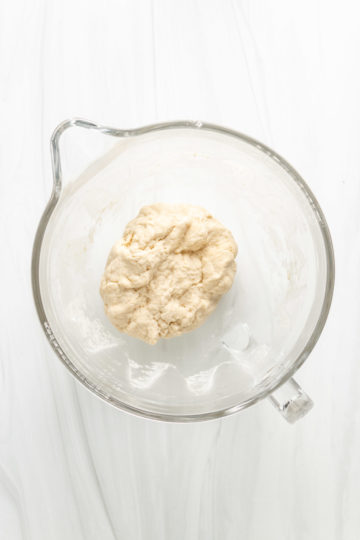 Top down view of sourdough naan dough in a glass bowl.