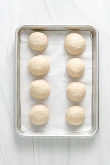 Top down view of rolled naan bread on a baking sheet.