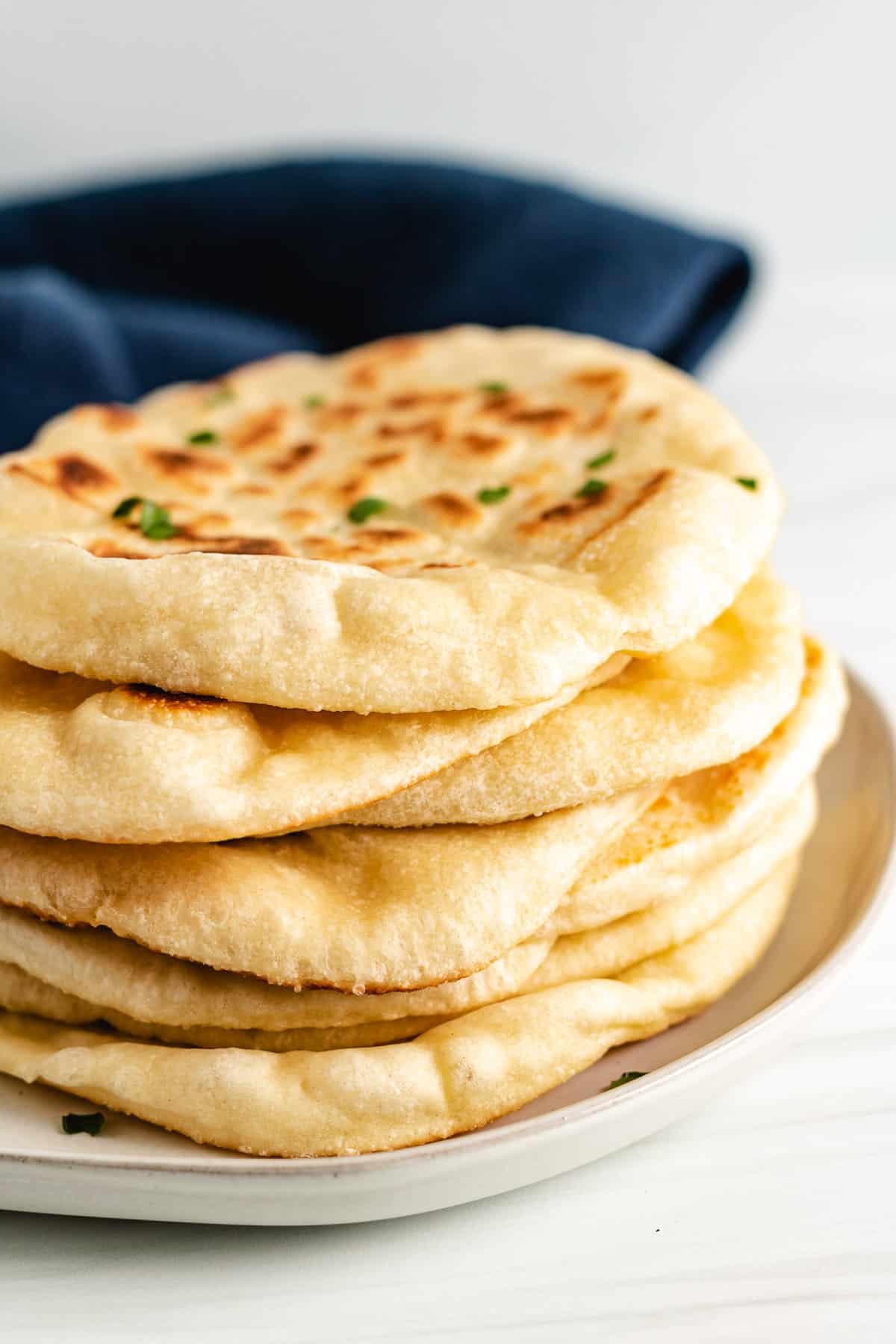 Stack of naan bread with a blue linen.