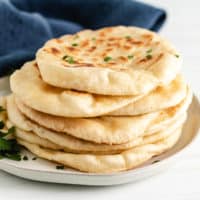 Several pieces of naan bread on a gray plate.