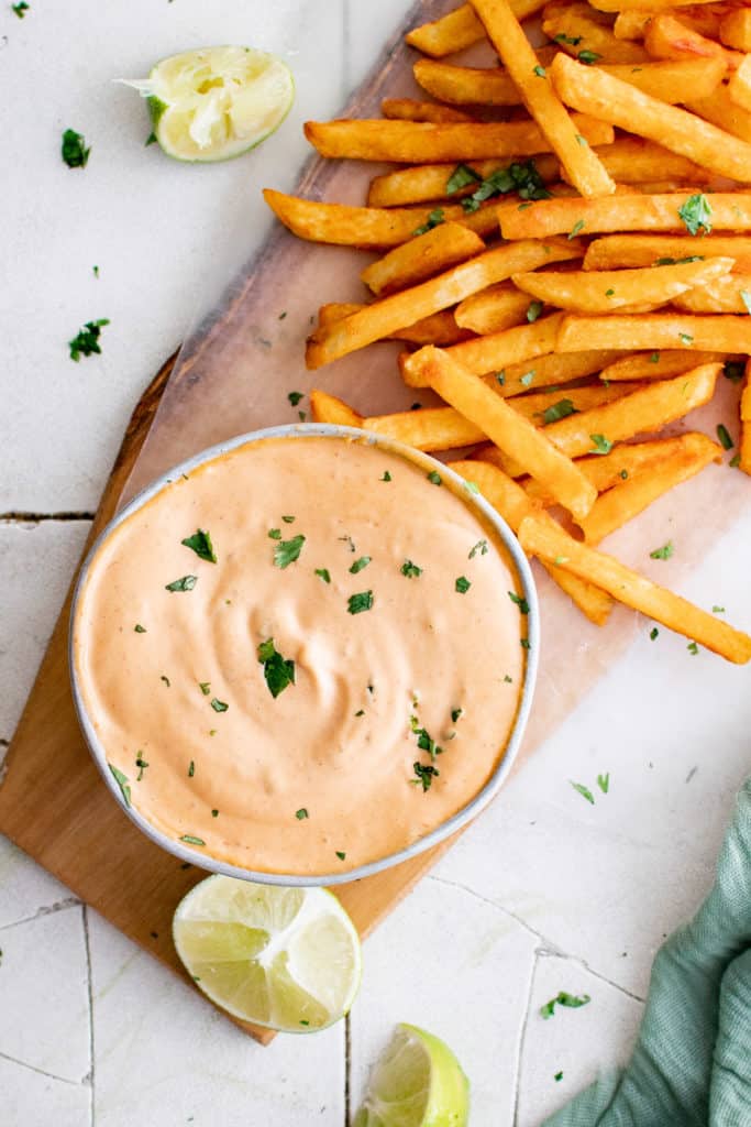 Top down view of chipotle mayo in a bowl next to sweet potato fries.