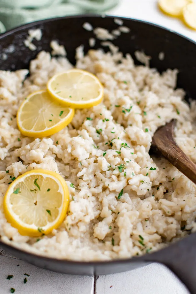 Close up view of risotto with lemon slices in a pan.