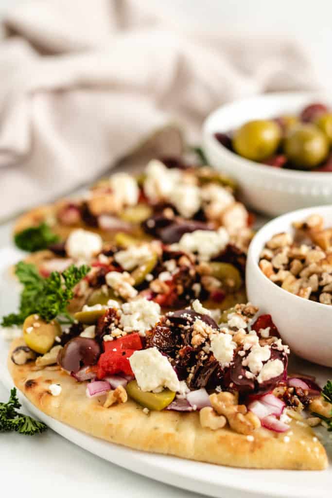 Sliced naan bread with olives and feta cheese.
