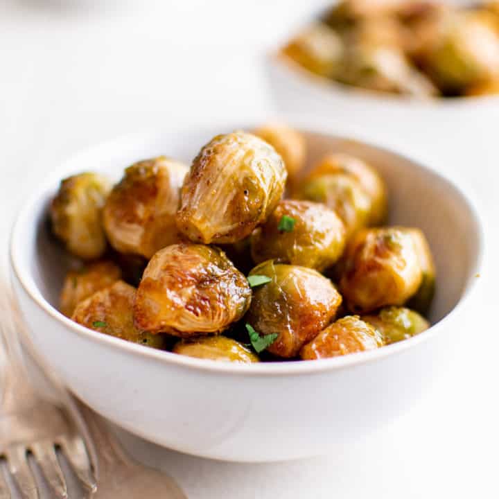 White bowl filled with honey sriracha brussel sprouts.