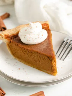 Slice of pie next to a fork on a plate.