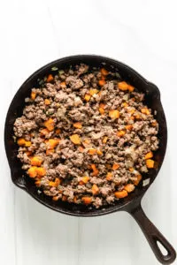 Top down view of carrots, onions, and ground beef in a pan.