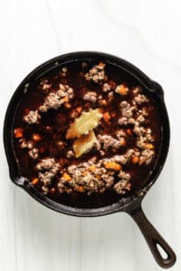 Top down view of ground beef with wine and beef broth.