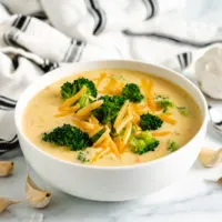 White bowl of broccoli cheddar soup.