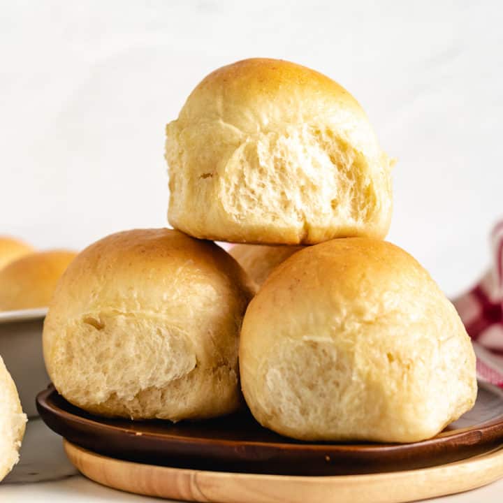 Pile of dinner rolls on a plate.
