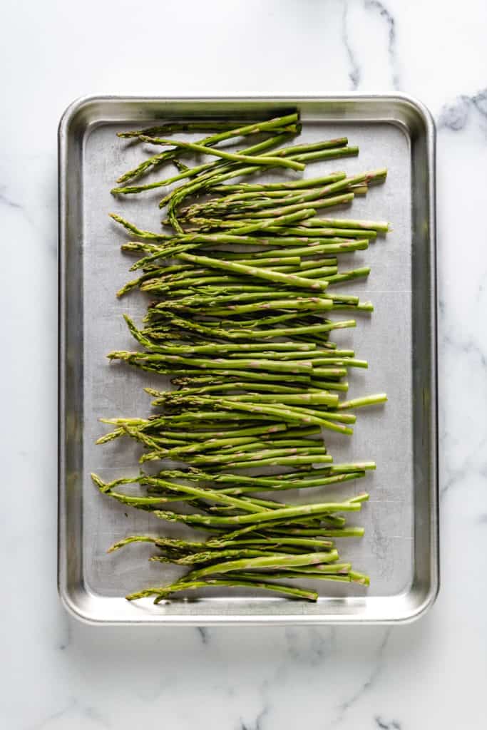 Top down view of asparagus spears on a baking sheet.