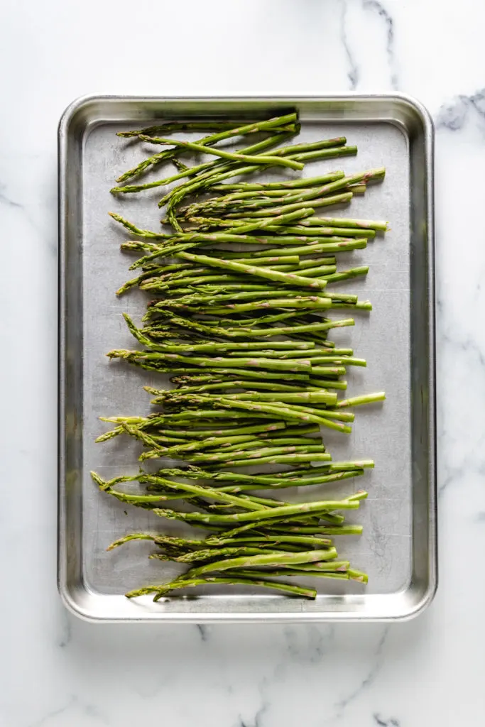 Top down view of asparagus spears on a baking sheet.