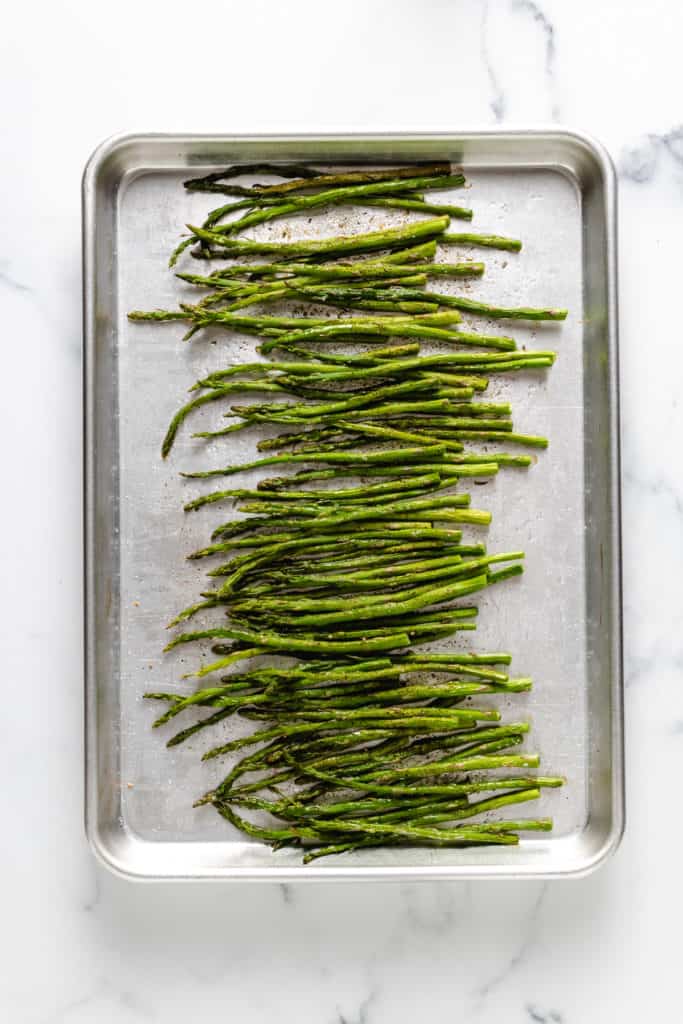 Top down view of seasoned asparagus on a pan.