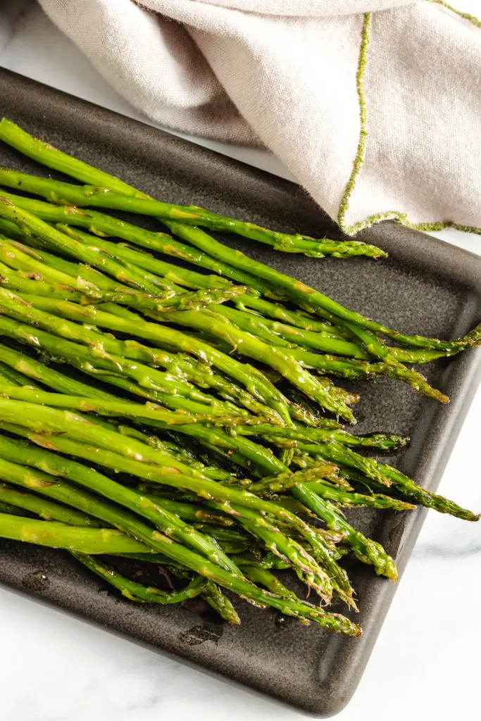 Roasted asparagus on a black plate.