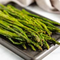 Roasted asparagus on a square plate.