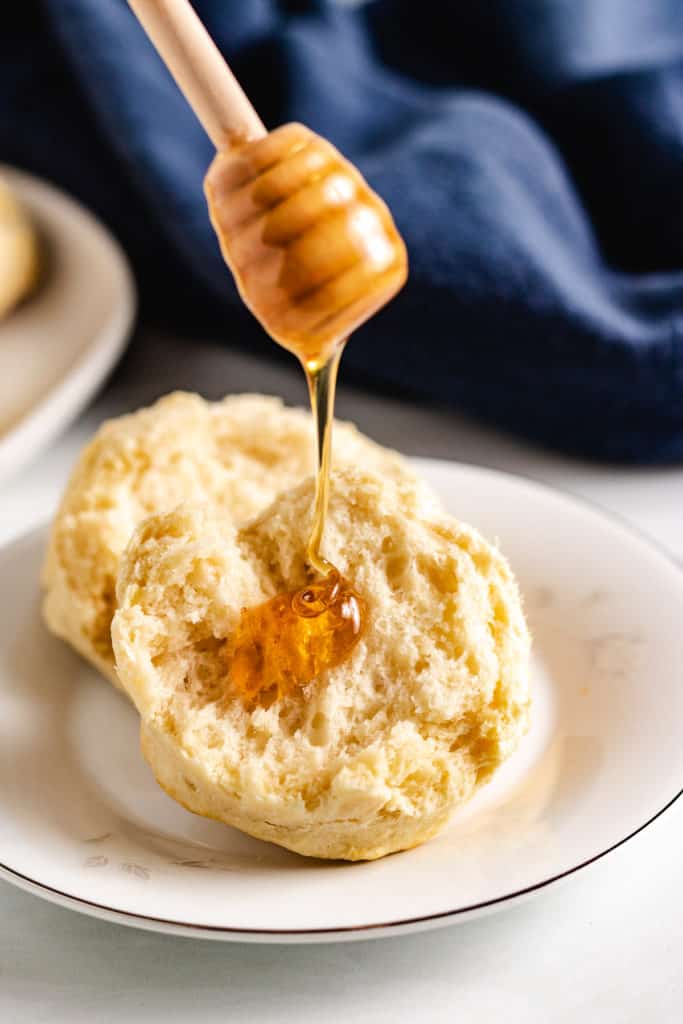 Sourdough biscuit being drizzled with honey.