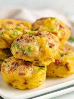 Bacon and egg muffins on a white serving dish.