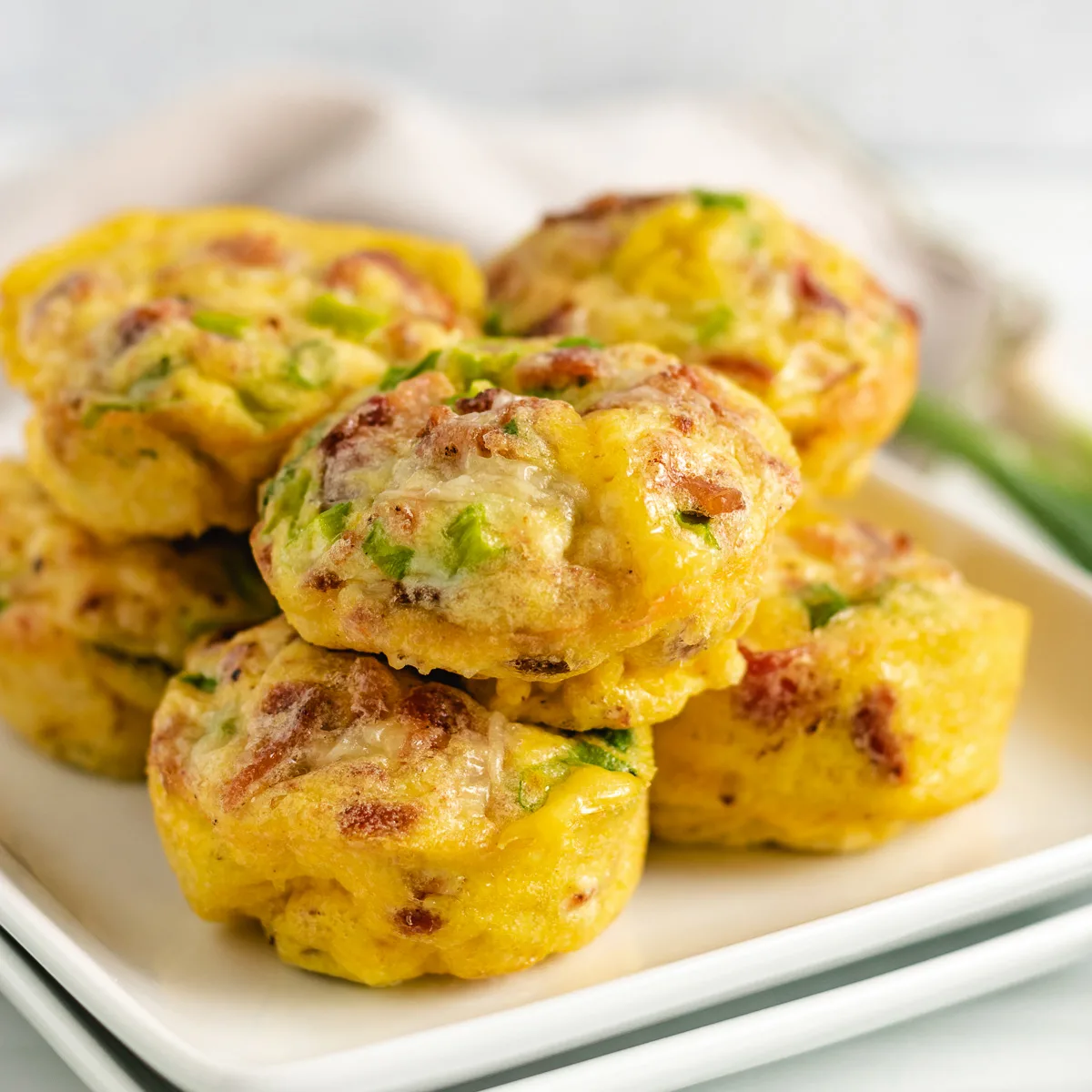 Bacon and egg muffins on a white serving dish.