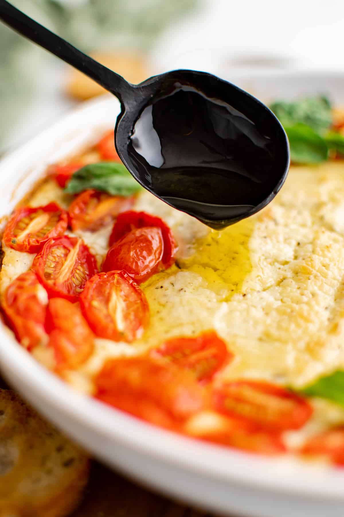 Olive oil being drizzled over baked goat cheese.