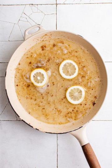 Lemons and capers cooking in a pan.