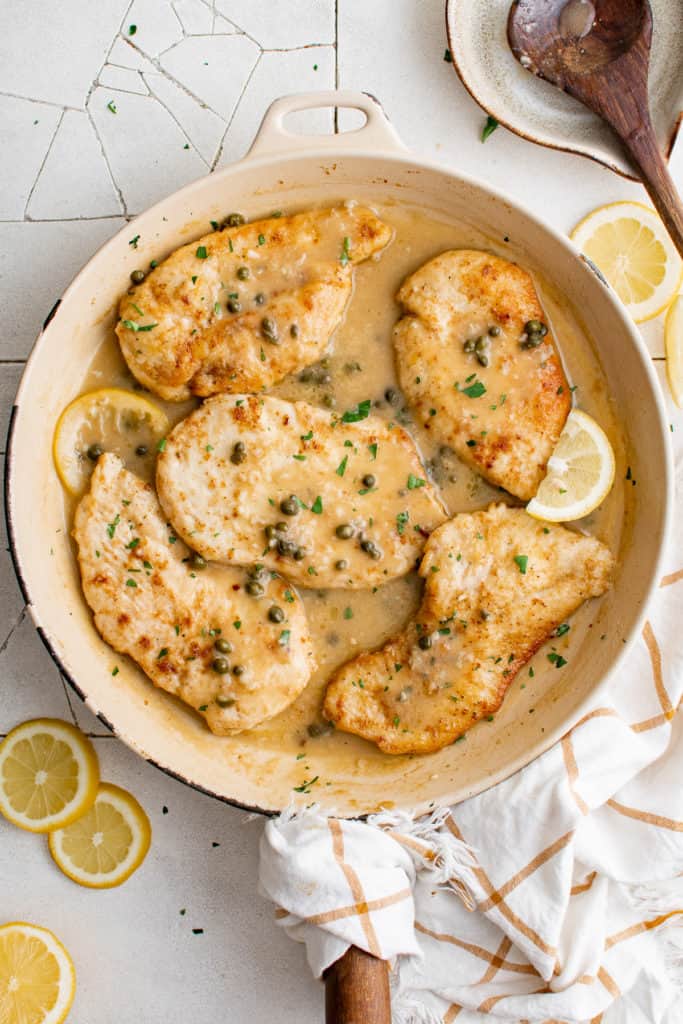 Top down view of chicken piccata cooking in a skillet.