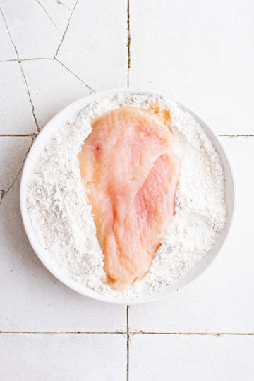 Chicken breast laying in flour.
