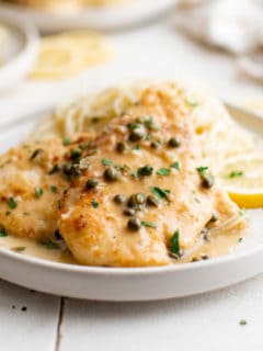 Gray plate with chicken piccata and caper sauce.