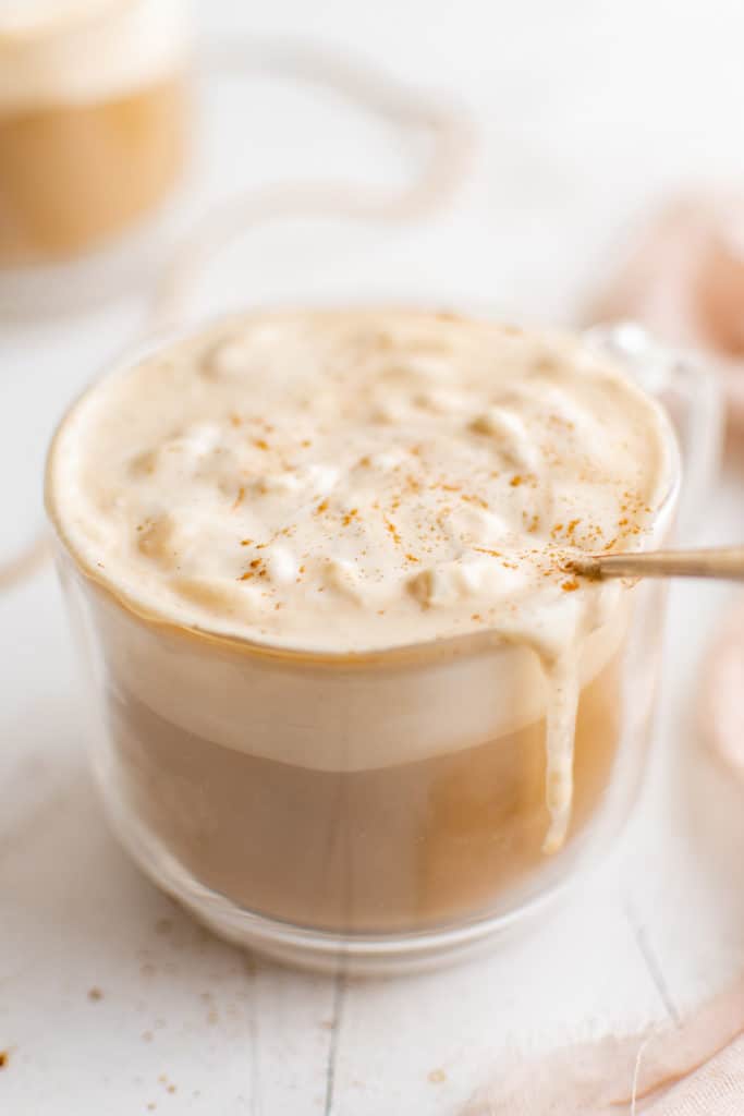 Hot eggnog latte in a glass mug.