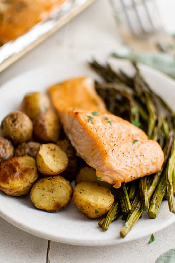 Salmon fillet on top of potatoes and asparagus.