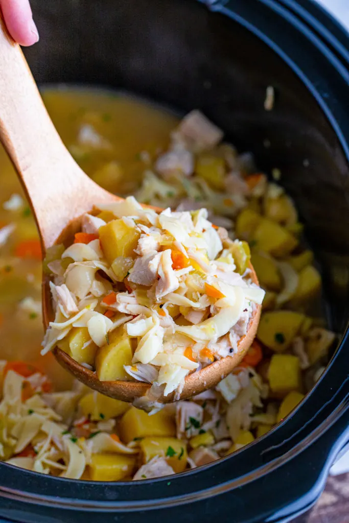 Ladle of soup over a crock pot.