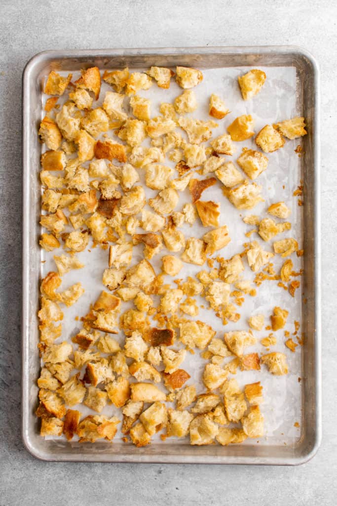 Top down view of croutons on a baking sheet.