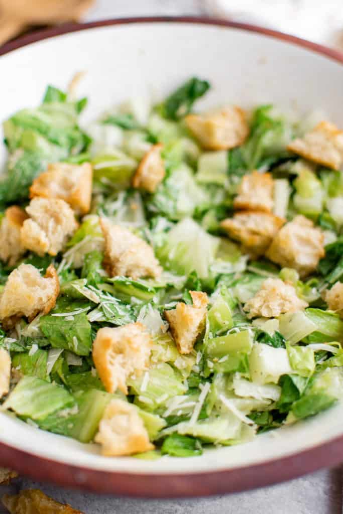 Close up view of caesar salad with dressing and croutons.