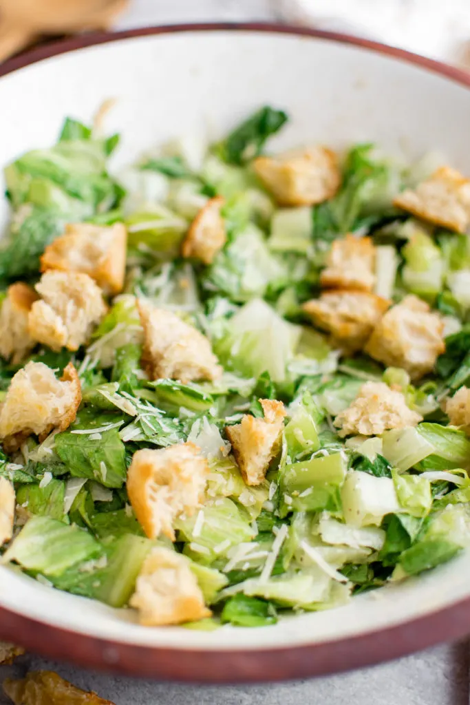 Close up view of caesar salad with dressing and croutons.