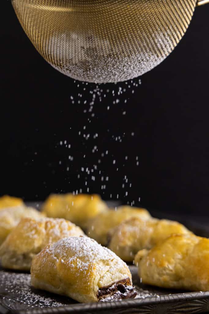 Powdered sugar falling on puff pastries with chocolate.