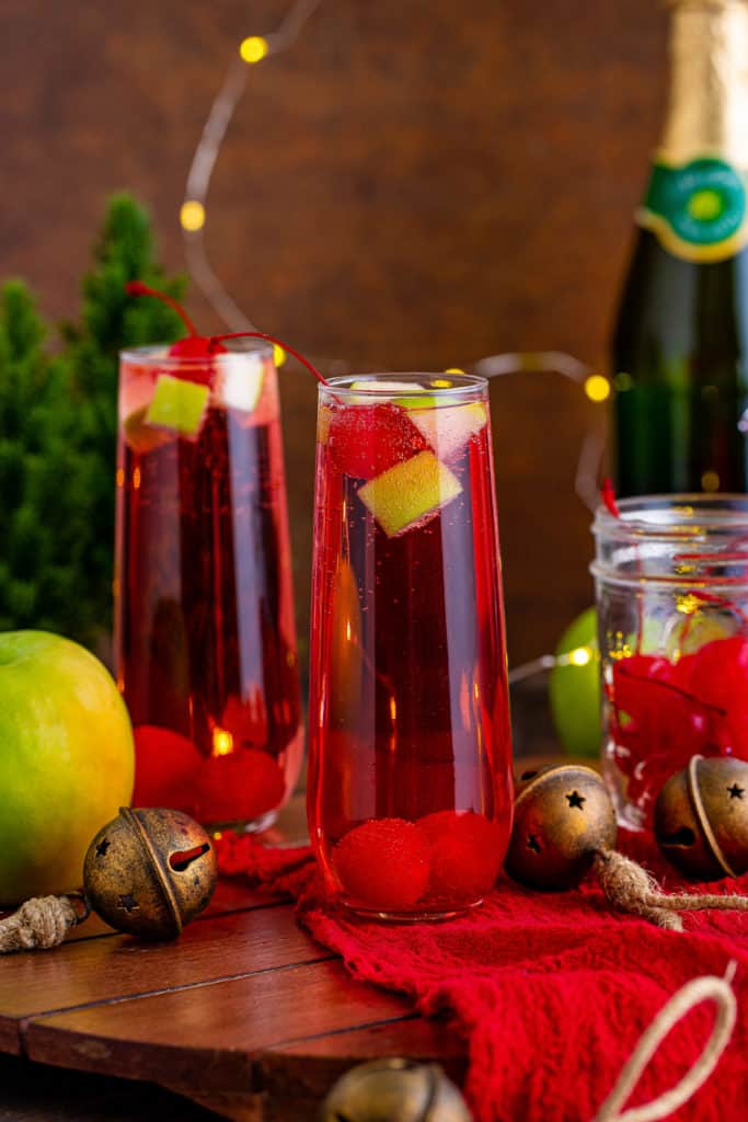 Christmas mocktail on a board with apples and sparkling apple cider.