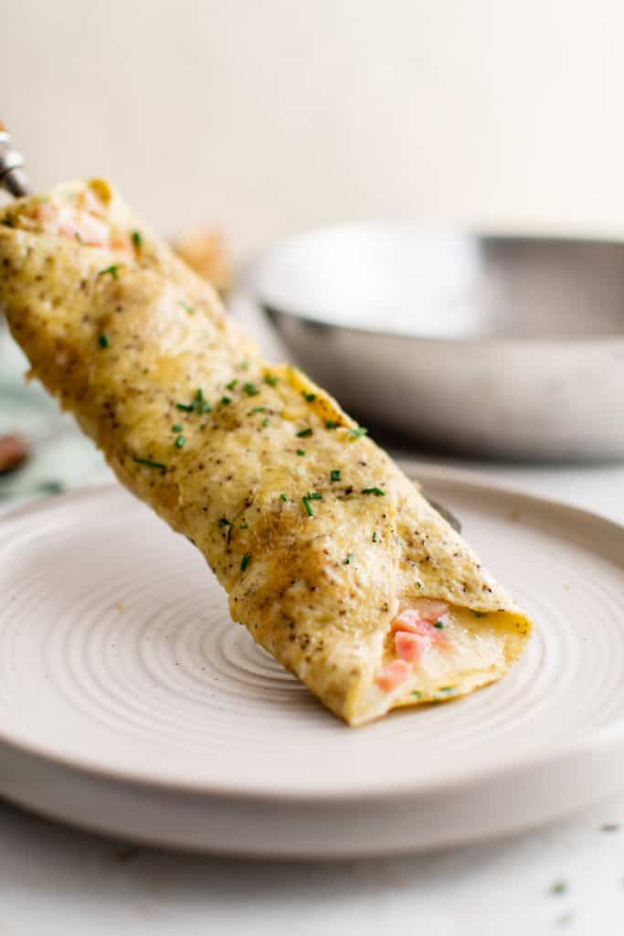 Spatula placing an omelette on a plate.