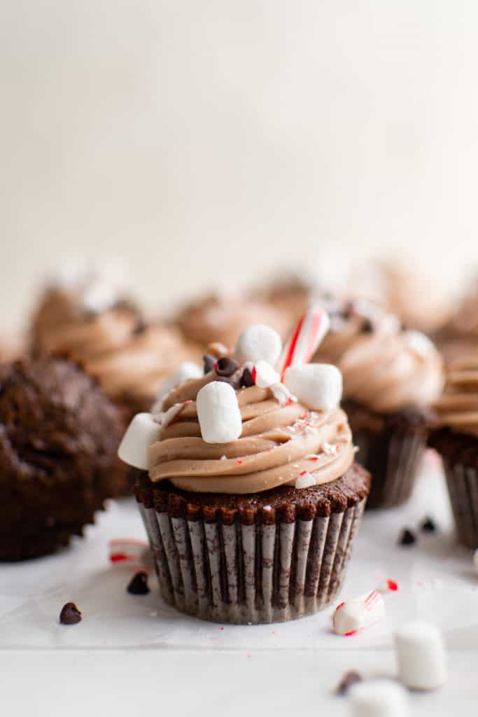 Side view of multiple hot chocolate cupcakes with marshmallows.