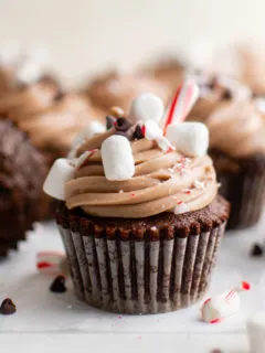 Several hot chocolate cupcakes with candy pieces.