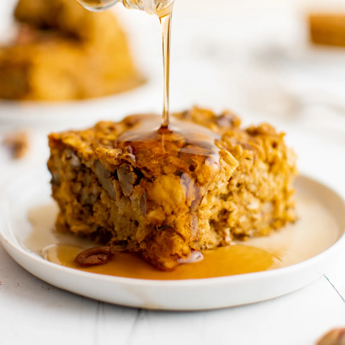 Maple syrup being drizzled on pumpkin baked oatmeal.