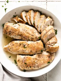 Top down view of four slow cooker chicken breasts in a bowl.