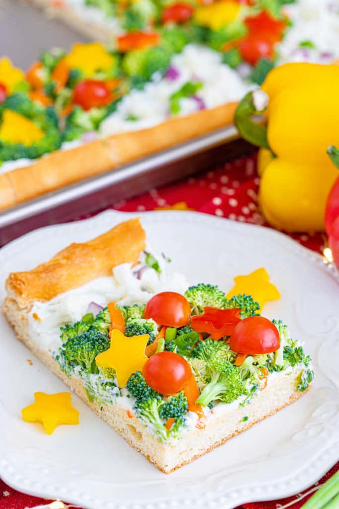 Crescent roll pizza slice topped with fresh vegetables.