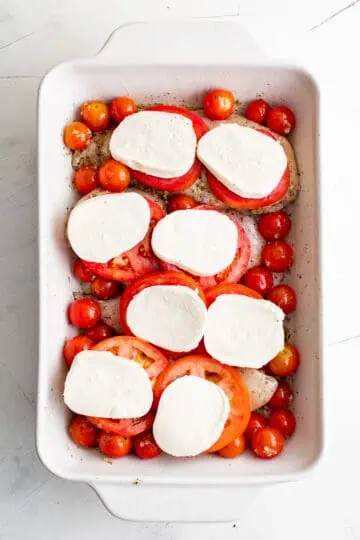 Mozzarella cheese slices laid on top of chicken breasts.