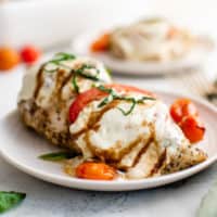 Side view of chicken caprese on a white dish.