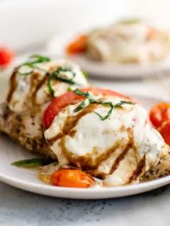 Side view of chicken caprese on a white dish.