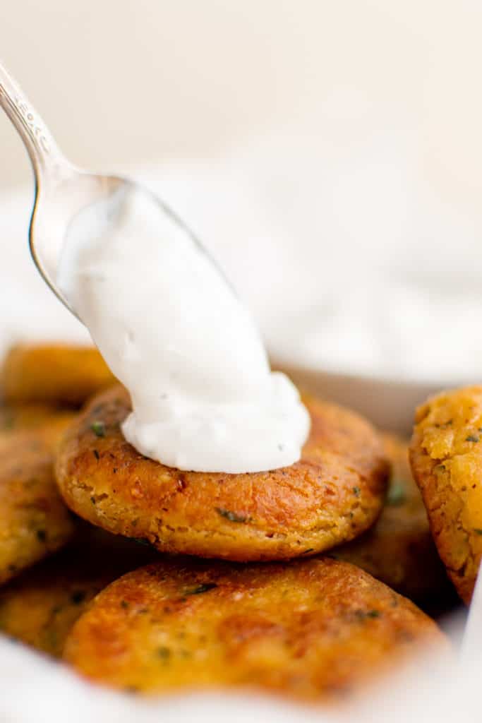 Spoon placing french onion dip on a fritter.