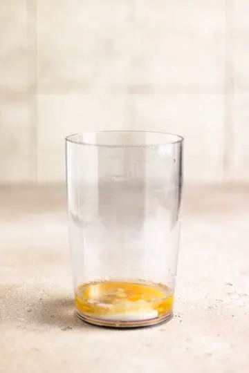 Egg, mustard, lemon juice, and vinegar in a plastic cup.